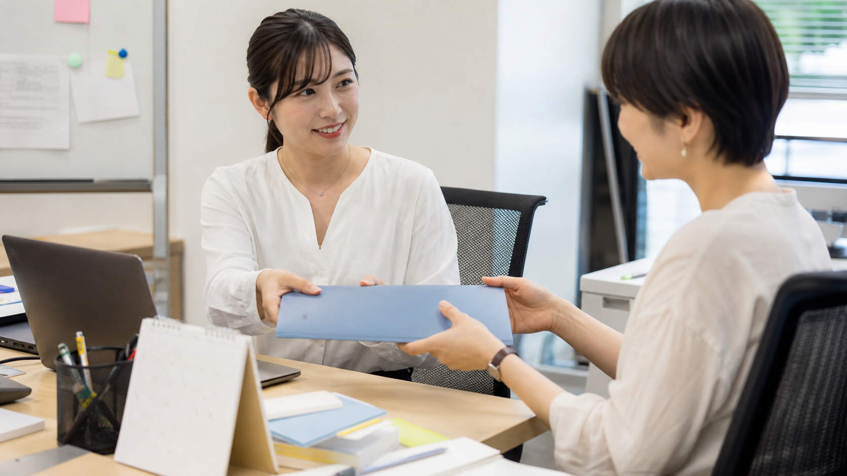 有給前に同僚へ引き継ぎ資料を渡す様子