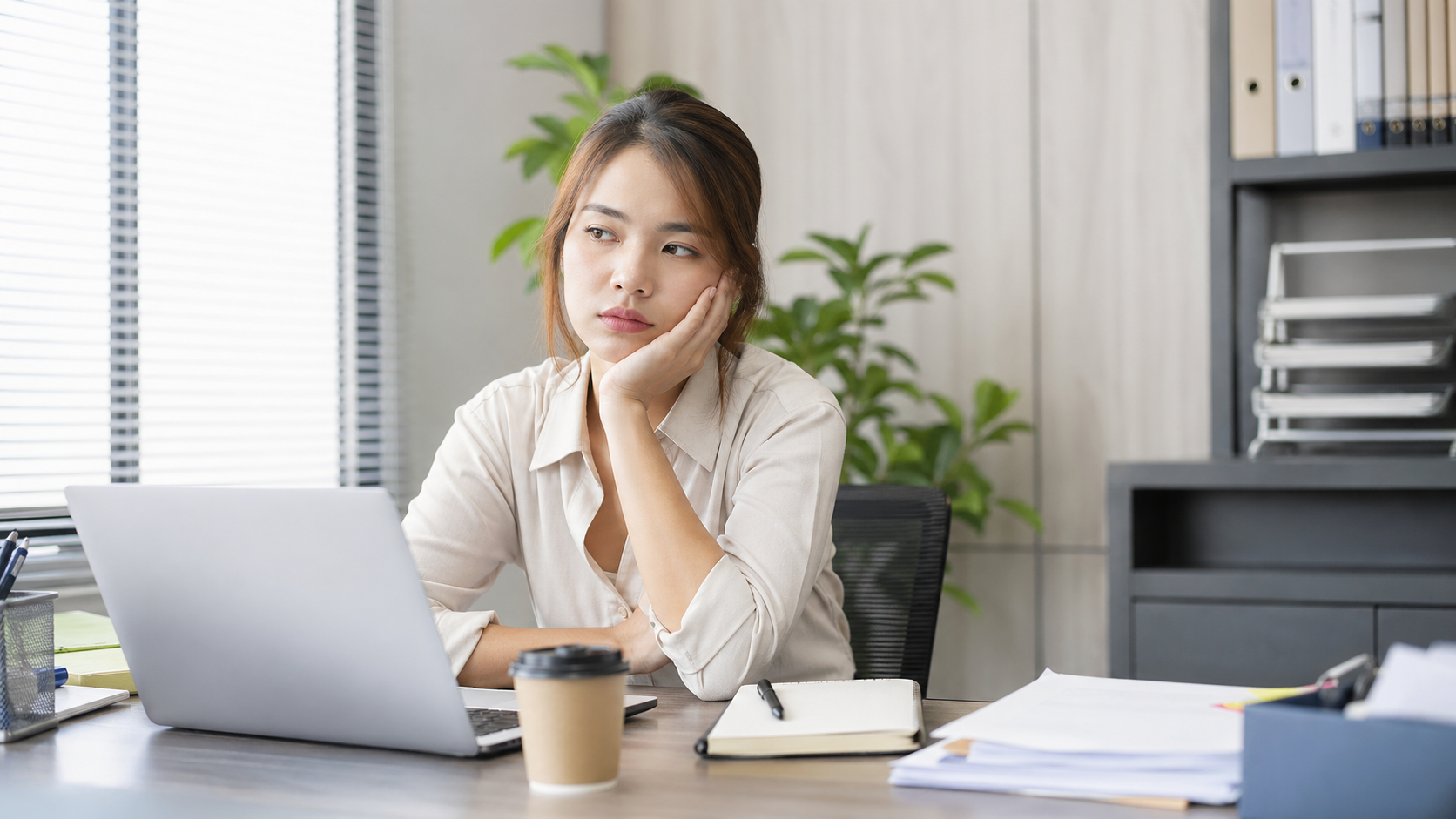 仕事が適当になる原因に悩む会社員が机で考えている様子