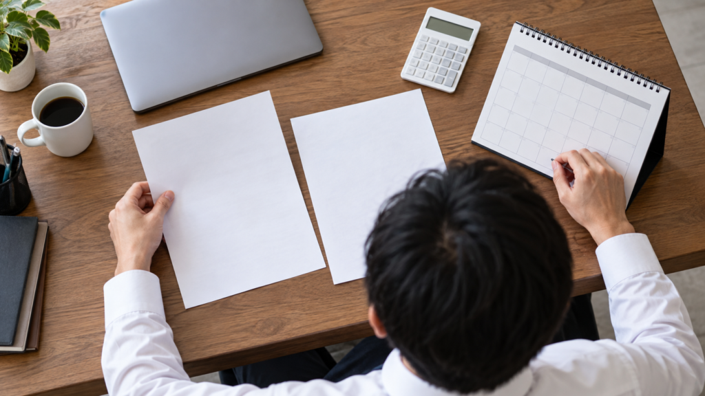 勤務予定と給与に関する書類を分けて机上で確認する会社員の手元