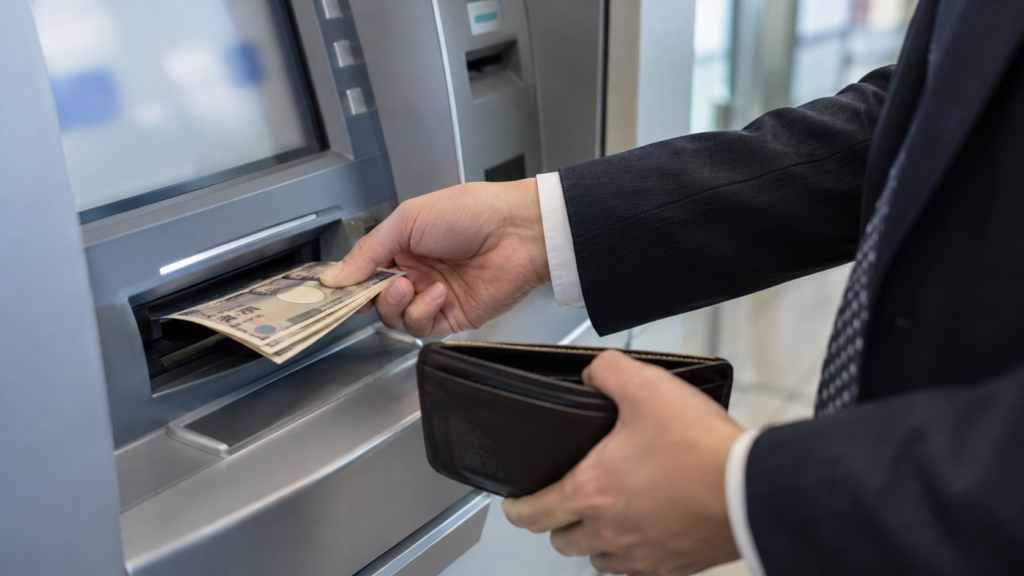 ATMで現金を受け取り財布に収める手元